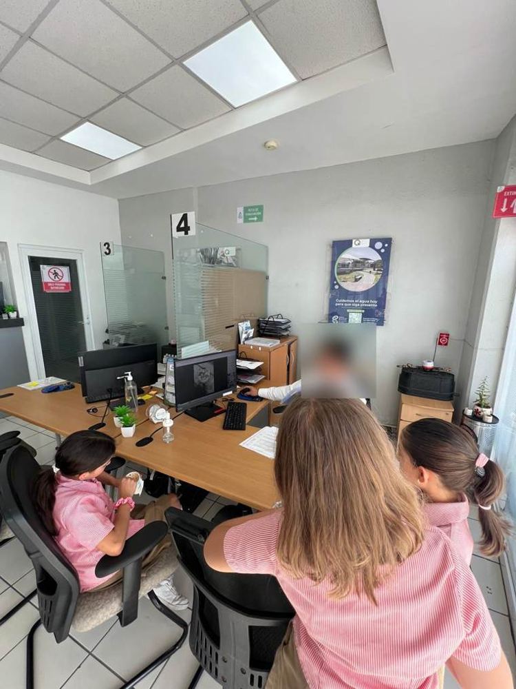 Las integrantes en una oficina de atención, frente a un funcionario que muestra algo en su pantalla